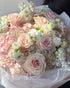 Large pastel bouquet with blush roses, white hydrangeas, and soft pink flowers wrapped in white paper