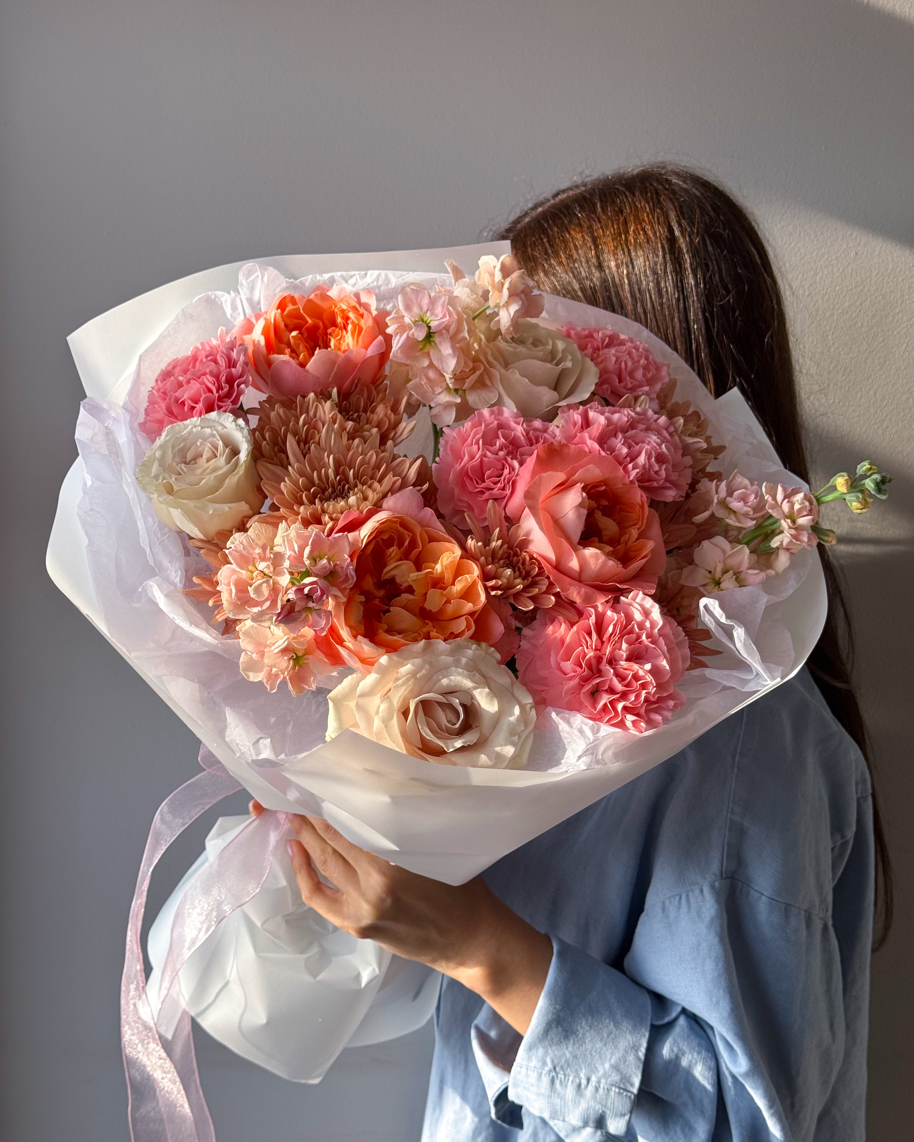 Close-up of “Sunset Glow” bouquet highlighting peach roses, coral blooms, and soft blush tones.