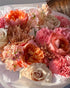 Close-up of “Sunset Glow” bouquet highlighting peach roses, coral blooms, and soft blush tones.